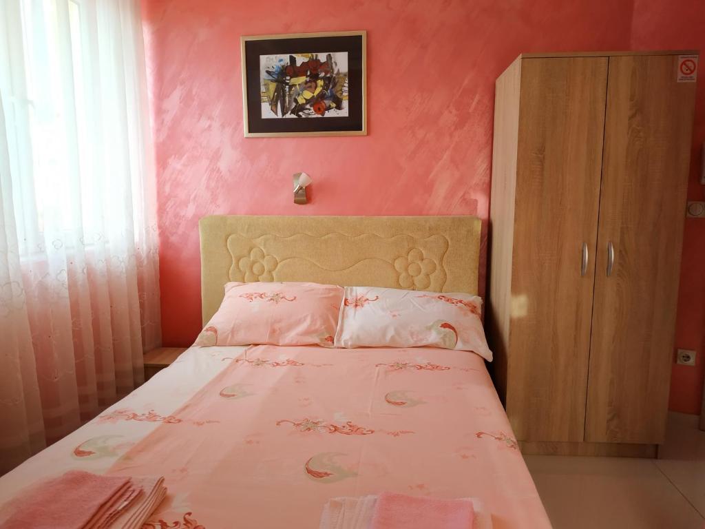Apartmani Spasic في ليسكوفاتش: غرفة نوم مع سرير بجدران وردية
