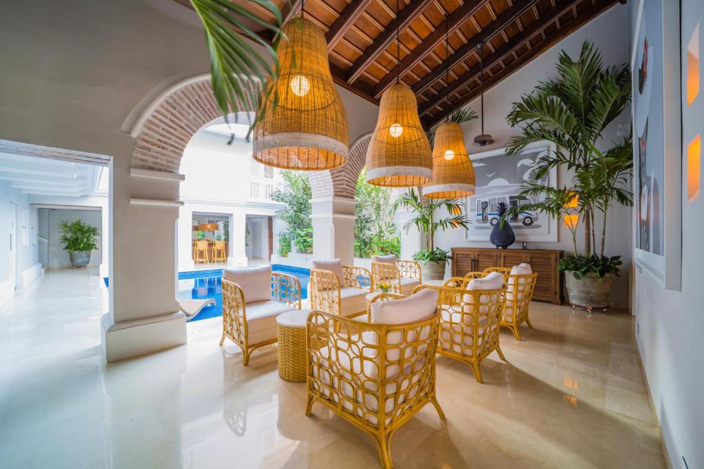 a dining room with chairs and tables and chandeliers at Casa La Merced by Mustique in Cartagena de Indias