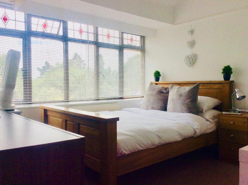 a bedroom with a wooden bed with windows at Gateway House in Didcot