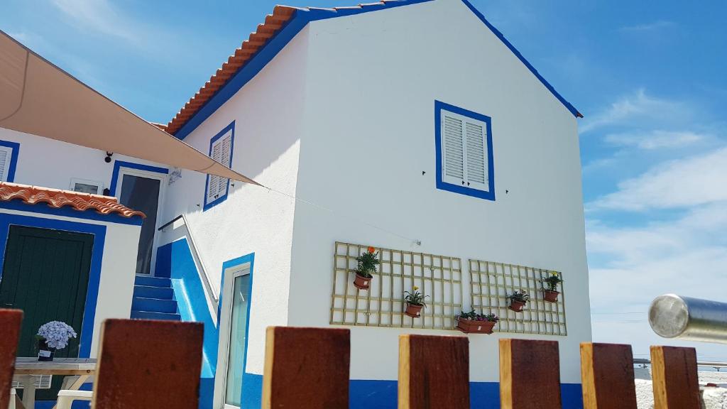 una casa con pareti bianche e blu e una recinzione di Casa Miramar ad Algarvia