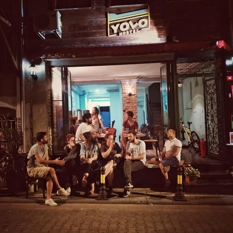 a group of people sitting on benches outside a building at yolohostel in Istanbul