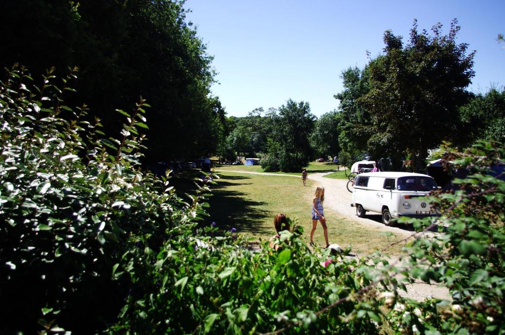 une fille marchant dans un champ avec une camionnette blanche dans l'établissement Camping La Bergerie, à La Chapelle-Achard