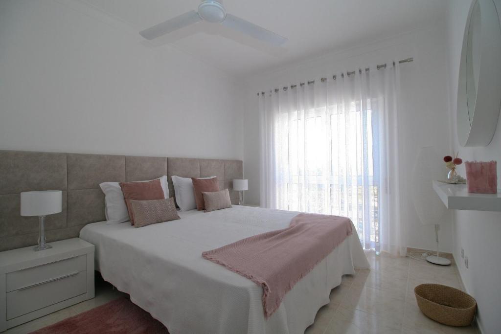 a white bedroom with a large bed and a window at Casa da Cidade in Lagos