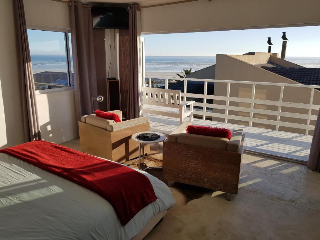 1 dormitorio con 1 cama y balcón con vistas al océano en Atlantic Loft - Open plan apartment with Sea Views, en Melkbosstrand