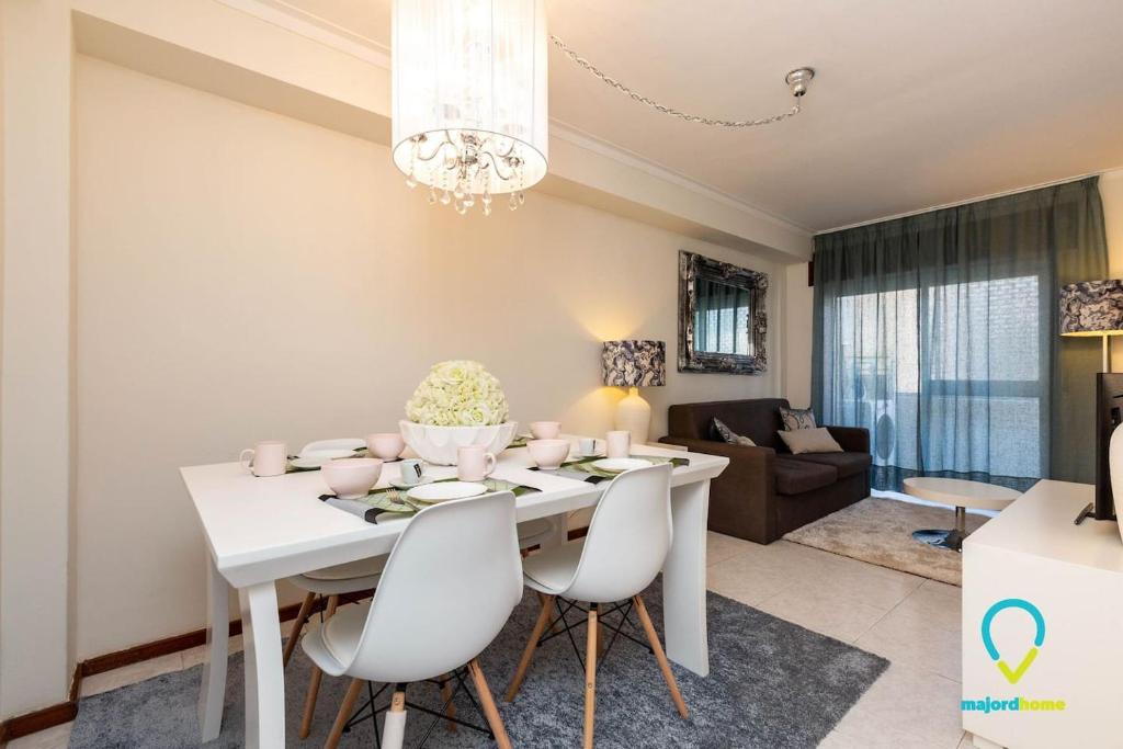 ein Esszimmer und ein Wohnzimmer mit einem weißen Tisch und Stühlen in der Unterkunft Camilo Apartment in Porto