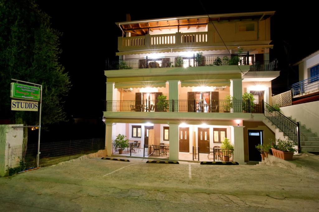 een groot wit gebouw met een balkon in de nacht bij Tommys House in Parga