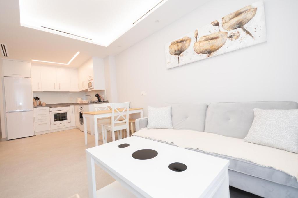 uma sala de estar branca com um sofá e uma mesa em Cubo's Apartamento Tivoli B4 em Benalmádena