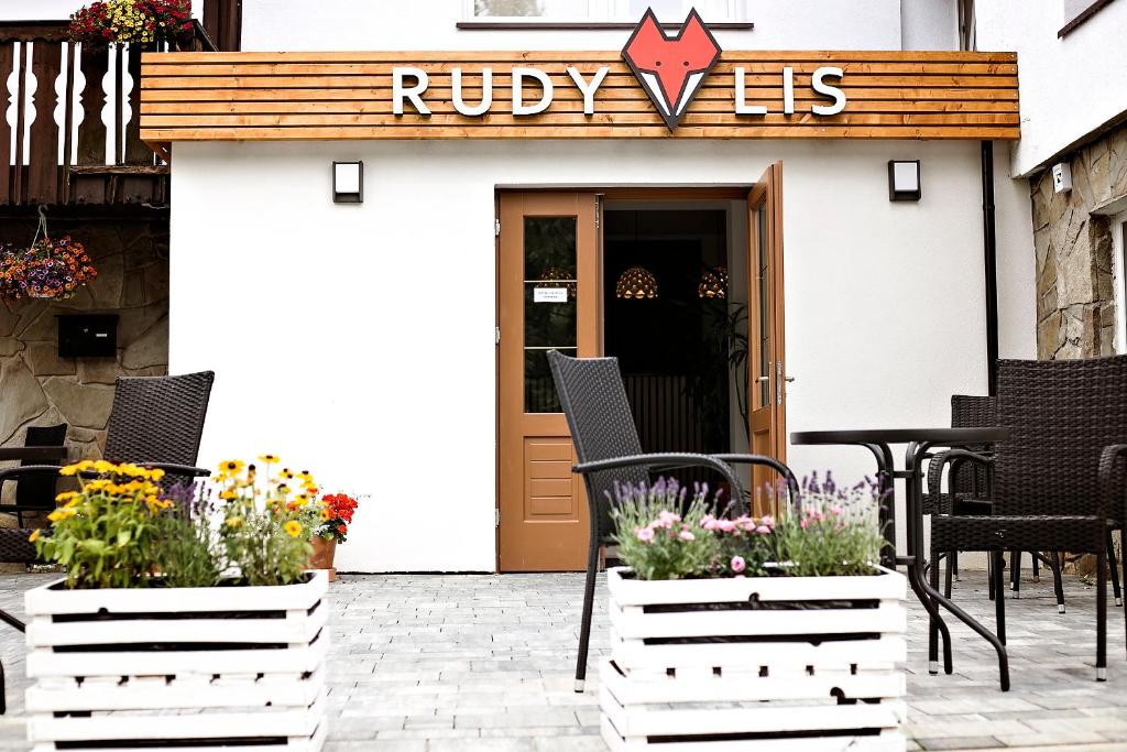 a patio with chairs and flowers in front of a building at Rudy Lis Szczyrk in Szczyrk