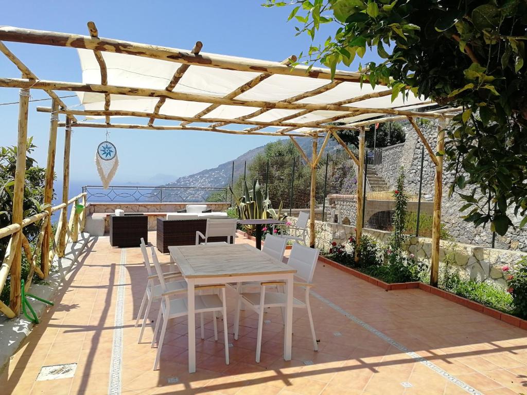 un patio con mesa y sillas bajo una pérgola en Villa Donna Antonia - Amalfi Coast en Conca dei Marini