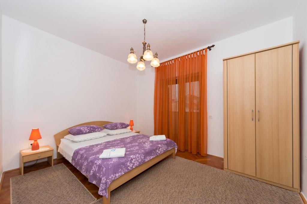 ein Schlafzimmer mit einem lila Bett und einem Schrank in der Unterkunft Apartman Zorica in Biograd na Moru