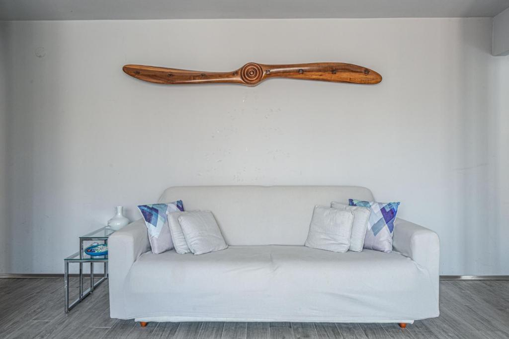 a wooden weapon hanging on a wall above a white couch at Suite Lido di VE Festival del Cinema in Quattro Fontane