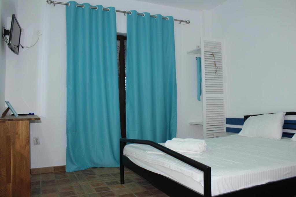 コスティネシュティにあるHacienda del Mar Costinestiのベッドルーム1室(青いカーテン付きのベッド1台付)
