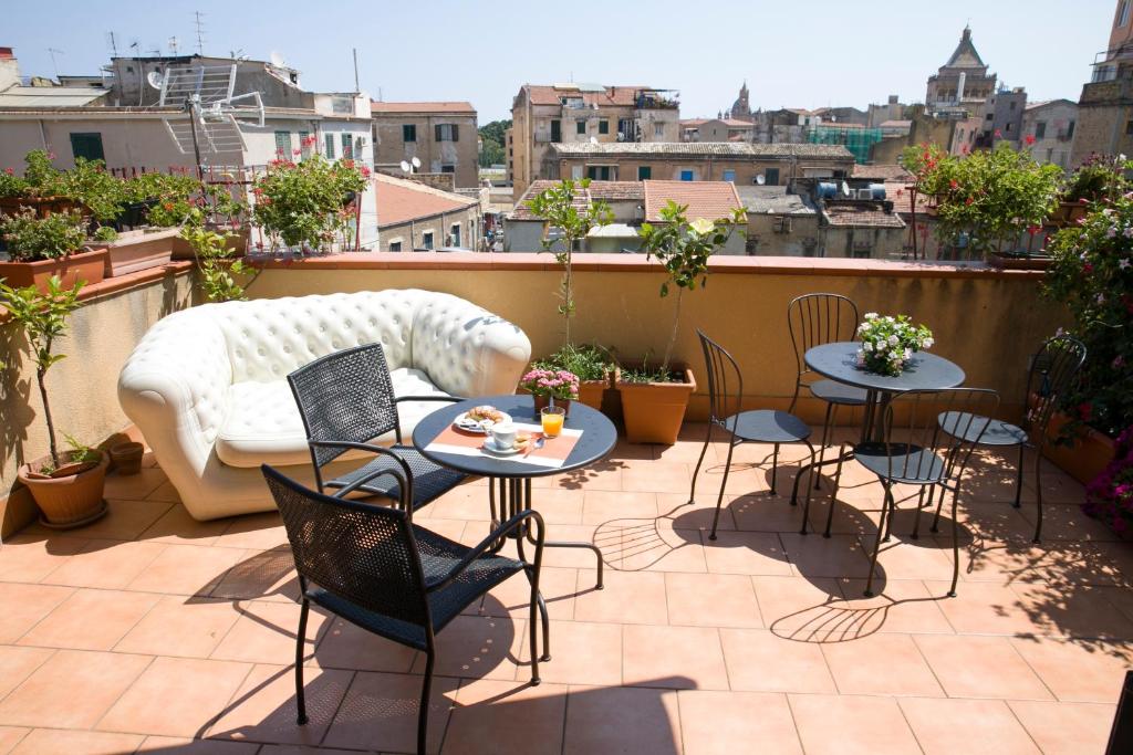 un patio avec des tables et des chaises ainsi qu'un canapé sur le toit dans l'établissement Residenza Normanna, à Palerme