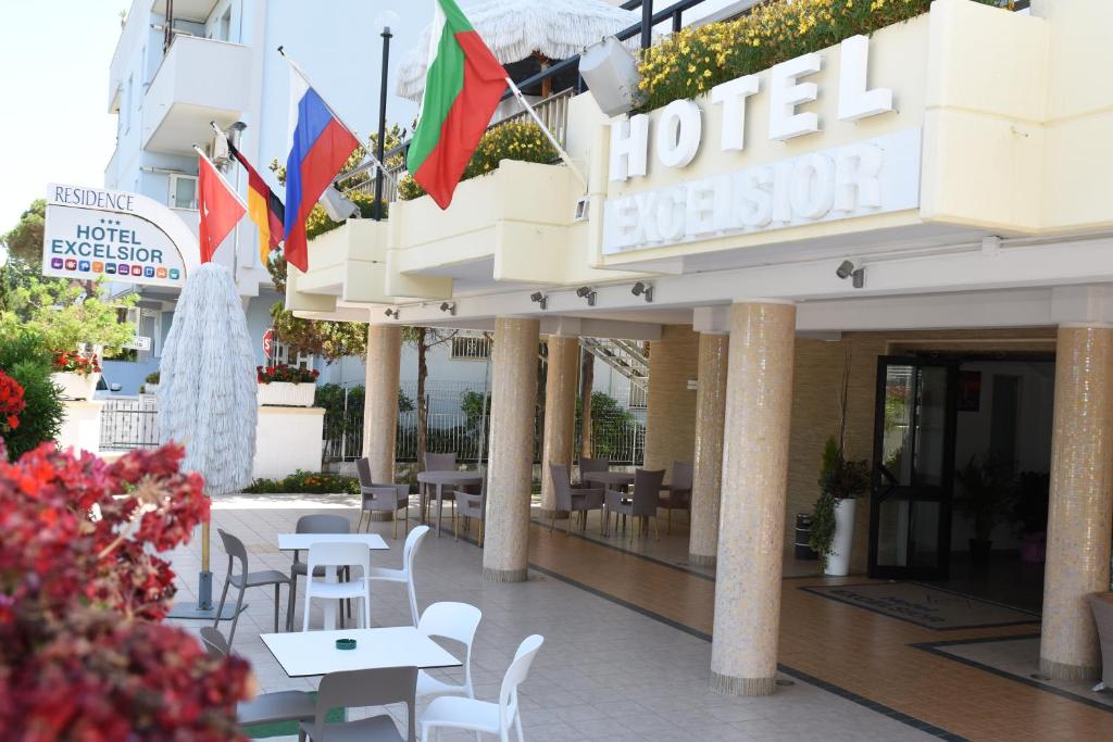 une entrée avec des tables, des chaises et des drapeaux dans l'établissement Hotel Excelsior, à Montesilvano