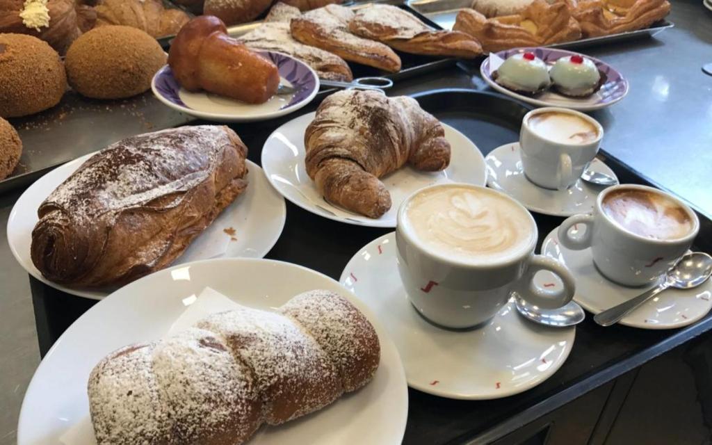 a table topped with plates of pastries and cups of coffee at Magico Sole in Porto Empedocle