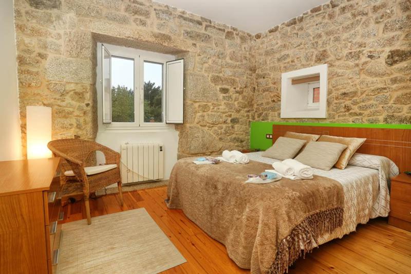 a bedroom with a bed and a desk and a stone wall at A Casa do Avó in Palas de Rei 