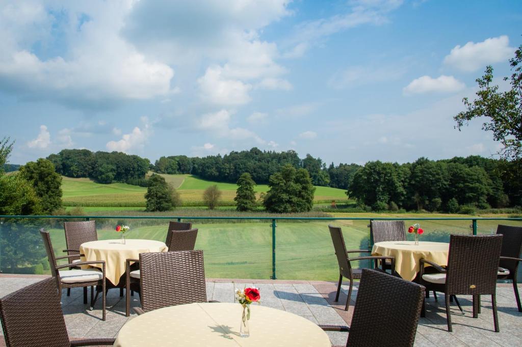 un patio con mesas y sillas y vistas a un campo de golf en Landhotel Moorhof, en Franking