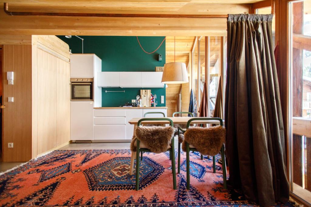 a kitchen with a table and chairs on a rug at Lenai & Linai Apartments in Lech am Arlberg