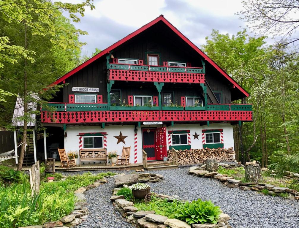 una casa roja y blanca con un jardín frente a ella en Grunberg Haus Inn & Cabins en Waterbury