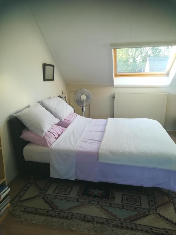 a large bed in a bedroom with a window at de Wielen in Schalkhaar