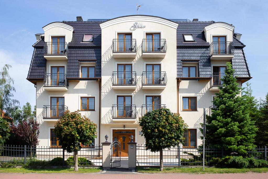 a tall white building with a black roof at Pensjonat Solar in Mielno