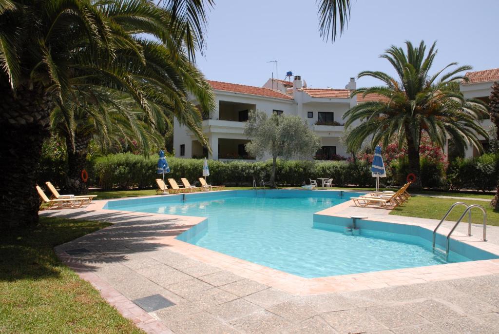 une piscine avec des chaises et un bâtiment dans l'établissement Niki Hotel Apartments, à Ialyssos