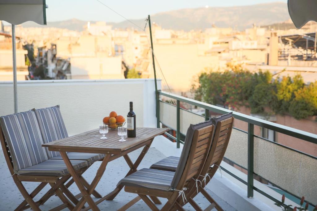 uma mesa e cadeiras numa varanda com uma garrafa de vinho em ivannas penthouse em Atenas