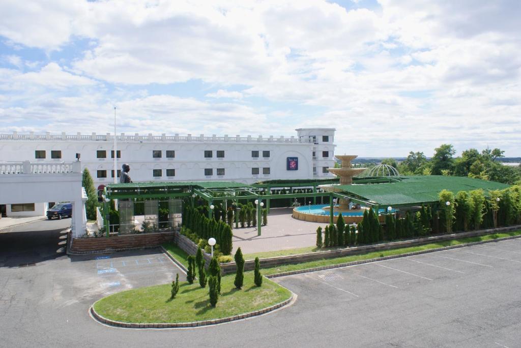 a large white building with a garden in front of it at Raritan Hotel in Edison