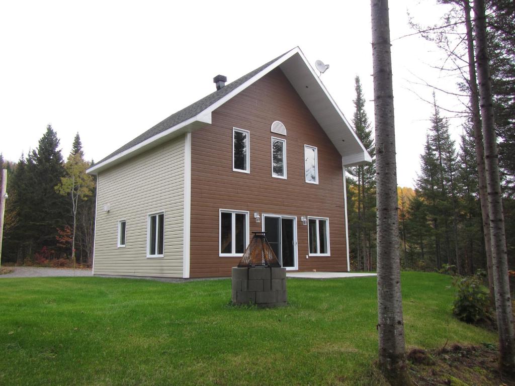 une maison marron et blanche dans une cour dans l'établissement domaine de la vallee, à Sainte-Rose-du-Nord