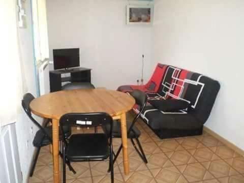 a table and chairs in a living room with a table and a chair at Gogo location 1 in Forest-Saint-Julien