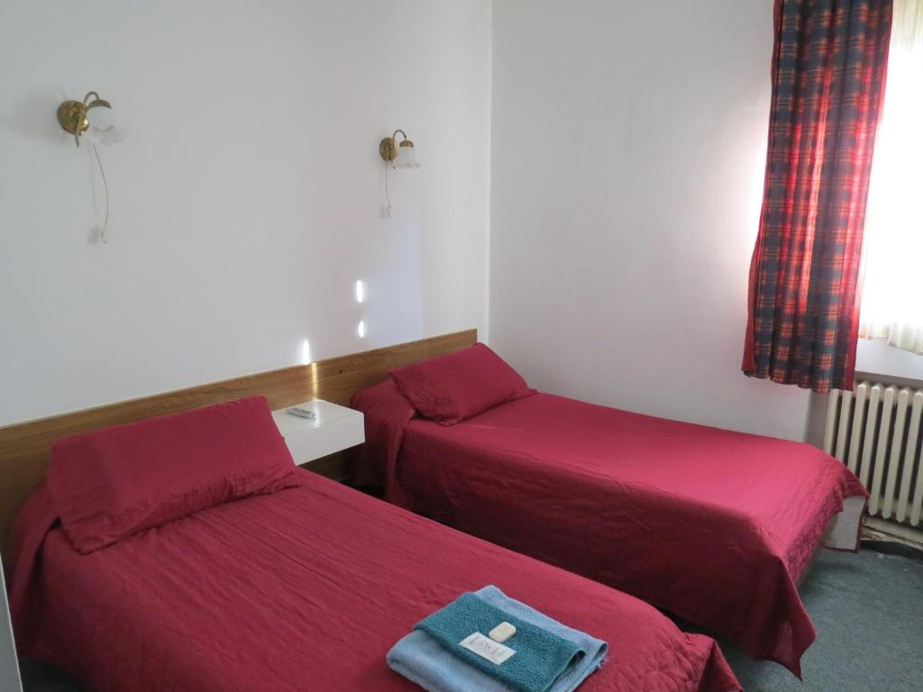 2 camas en una habitación pequeña con sábanas rojas en Hotel Oviedo en Río Gallegos