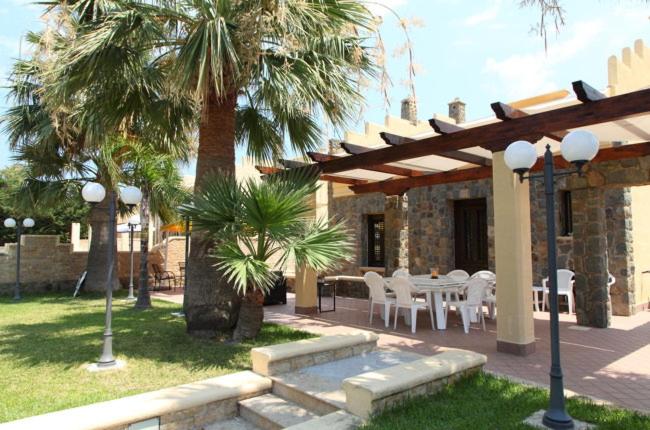 a patio with a table and chairs and palm trees at Villa lipari in Cefalù