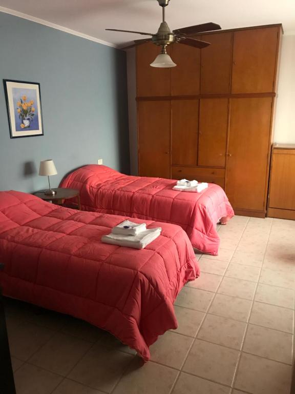 two beds in a room with red blankets at Departamento a 200 mts de la laguna in Chascomús