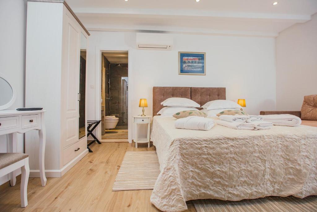 a white bedroom with two beds and a desk at Boutique Room Kaliopi in Hvar