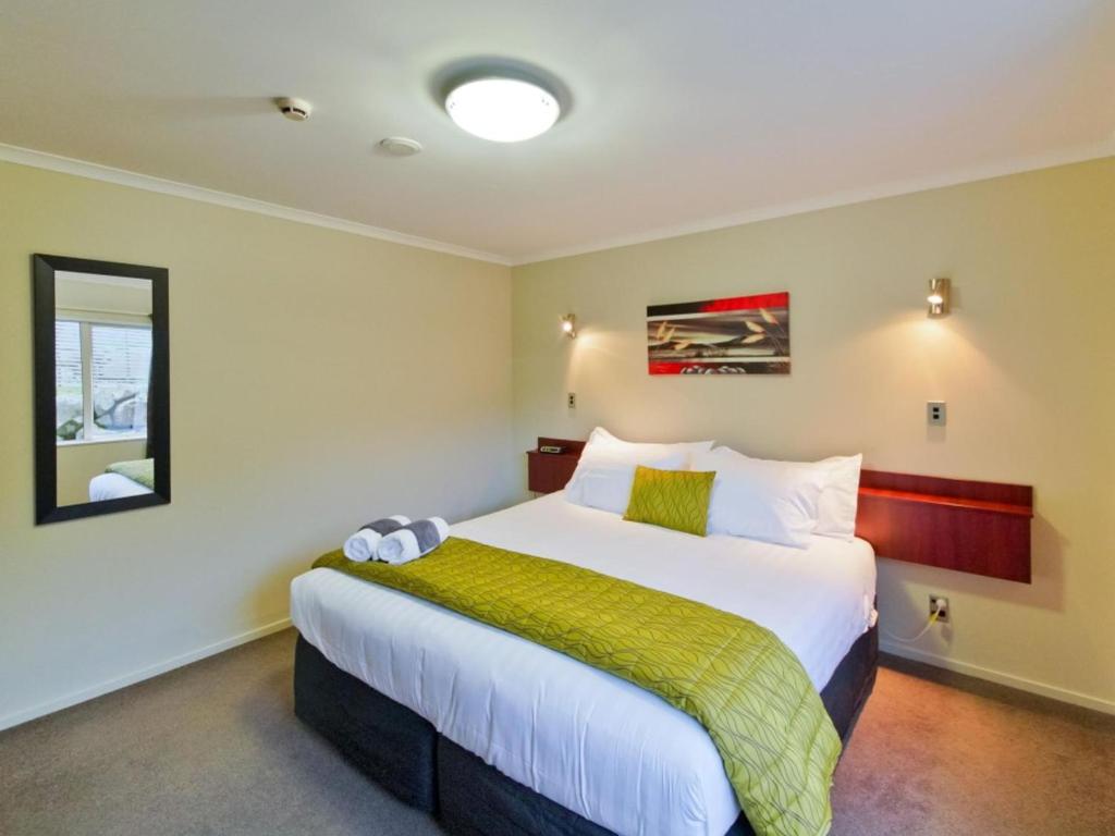 a bedroom with a large bed with a green blanket at ASURE Avenue Motor Lodge in Timaru