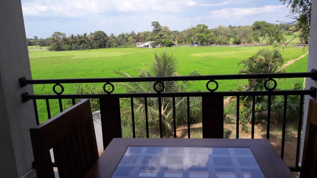 d'un balcon avec une table et une vue sur un champ. dans l'établissement Risenlak Holiday Resort, à Polonnâruvâ