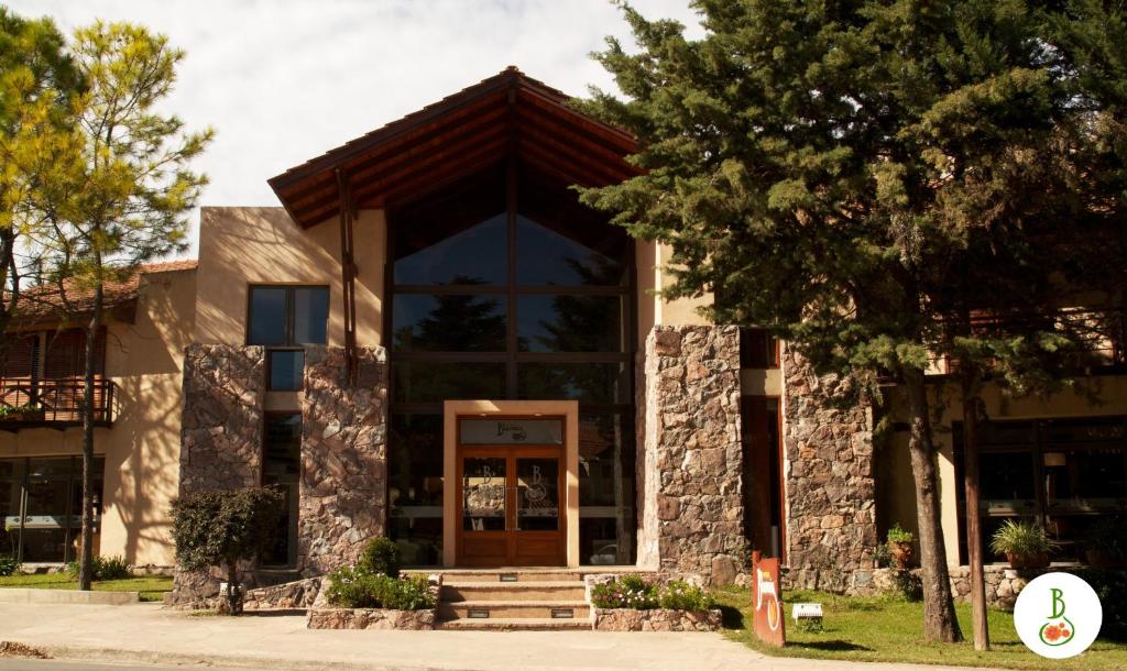 a building with a wooden door and a tree at Hotel Blumig in Villa General Belgrano