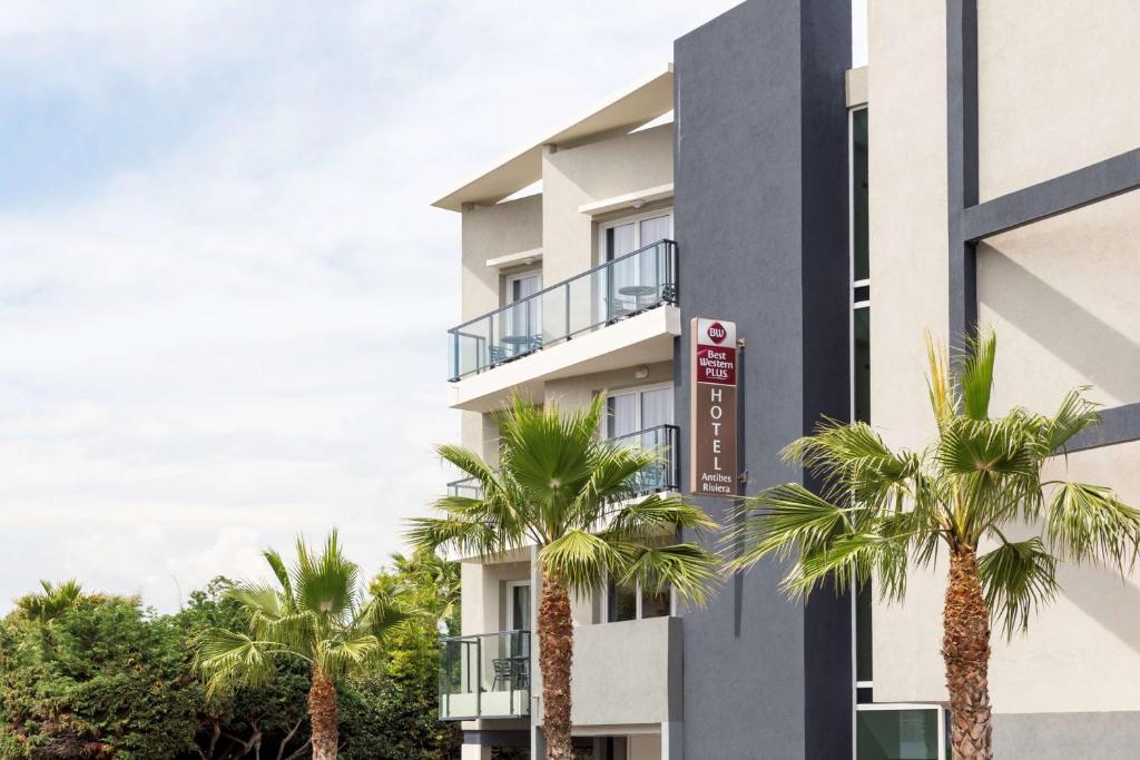 a building with palm trees in front of it at Best Western Plus Antibes Riviera in Antibes