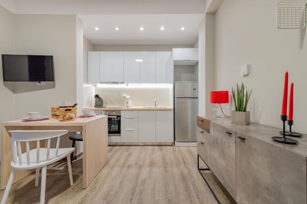 a kitchen with white cabinets and a table with a chair at Stylish & Bright Apartment in the City Centre in Zakynthos Town