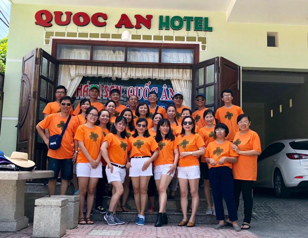 a group of people wearing orange shirts in front of a hotel at Quoc An Hotel in Long Hai