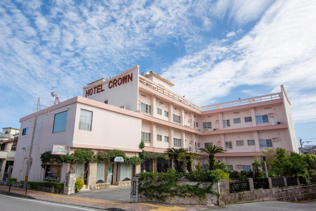 a large pink building with a sign on it at Crown Hotel Okinawa in Okinawa City