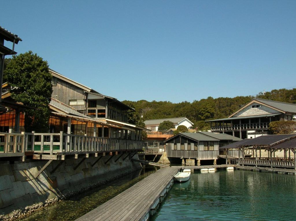 un grupo de edificios junto a un río con un barco en Hiogiso, en Shima