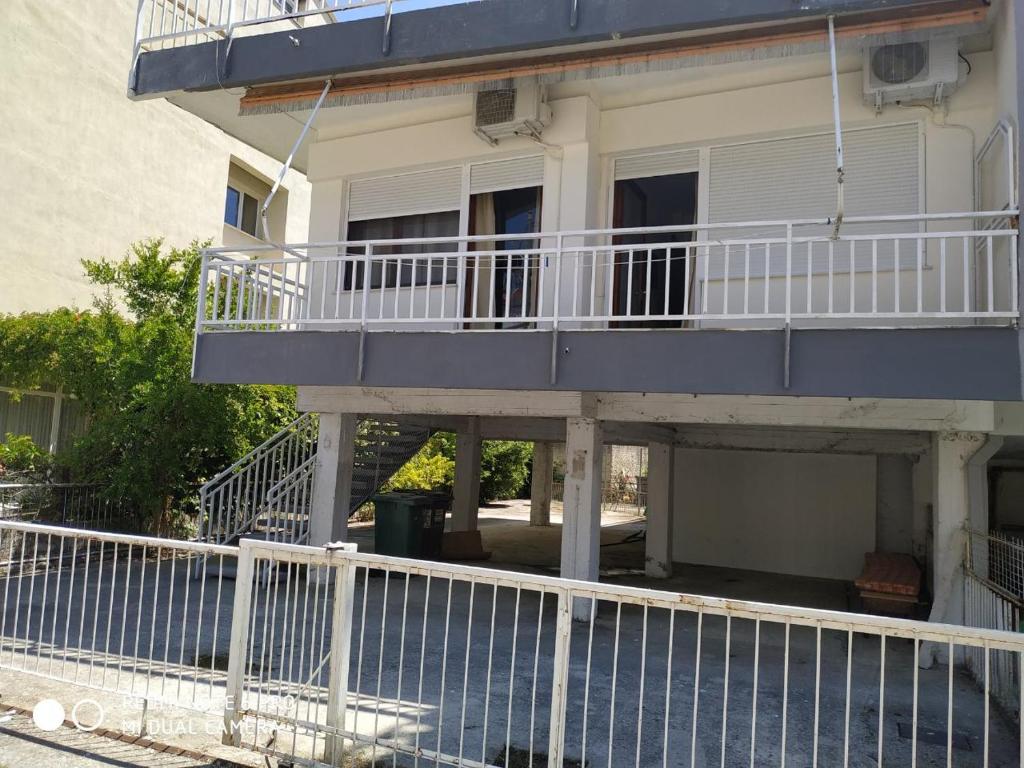 a building with a balcony and a fence at White Coral in Paralia Katerinis