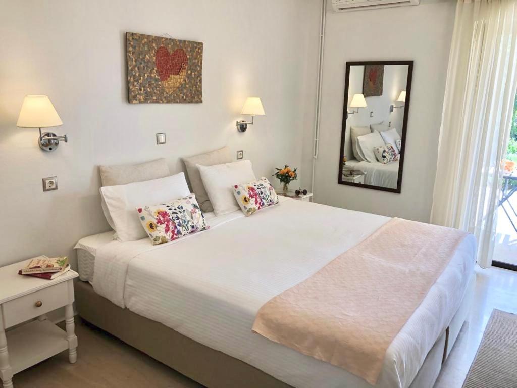 - une chambre avec un grand lit blanc et un miroir dans l'établissement NIKOLETA'S CORFU APARTMENTS, à Gouviá