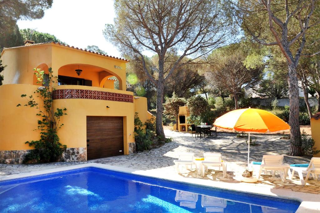 a house with a swimming pool and an umbrella at Pinedes in L'Escala