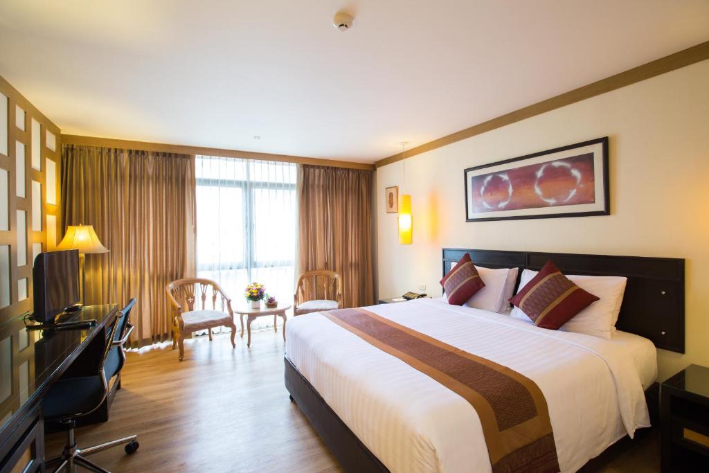 um quarto de hotel com uma cama grande e uma secretária em The Tarntawan Hotel Surawong Bangkok em Bangkok