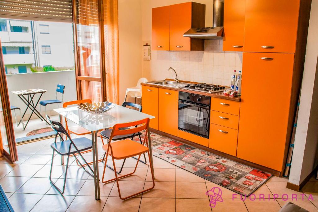 eine Küche mit orangefarbenen Schränken und einem Tisch mit Stühlen in der Unterkunft casa vacanze da Nico in Parma