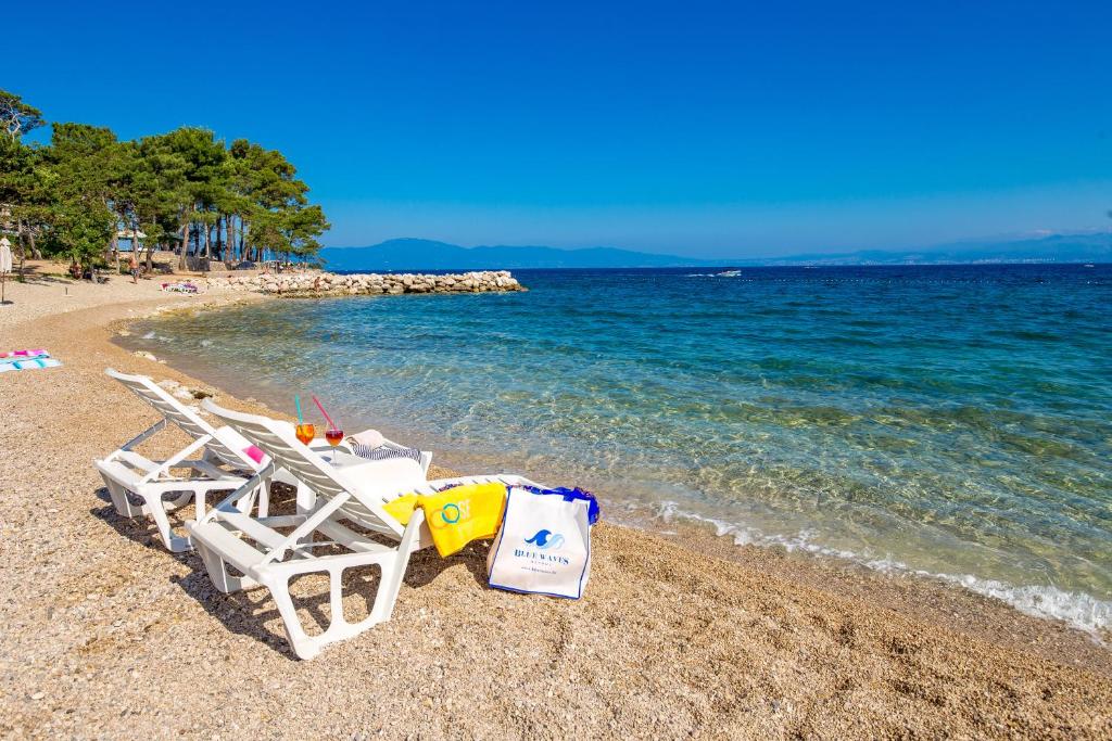 a beach with two lounge chairs and the ocean at Blue Waves Resort in Malinska