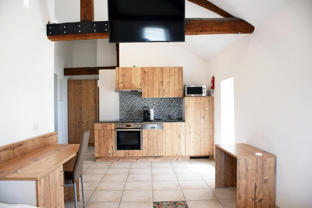 cocina con armarios de madera, mesa y TV en Apartment´s Marchtrenk en Marchtrenk