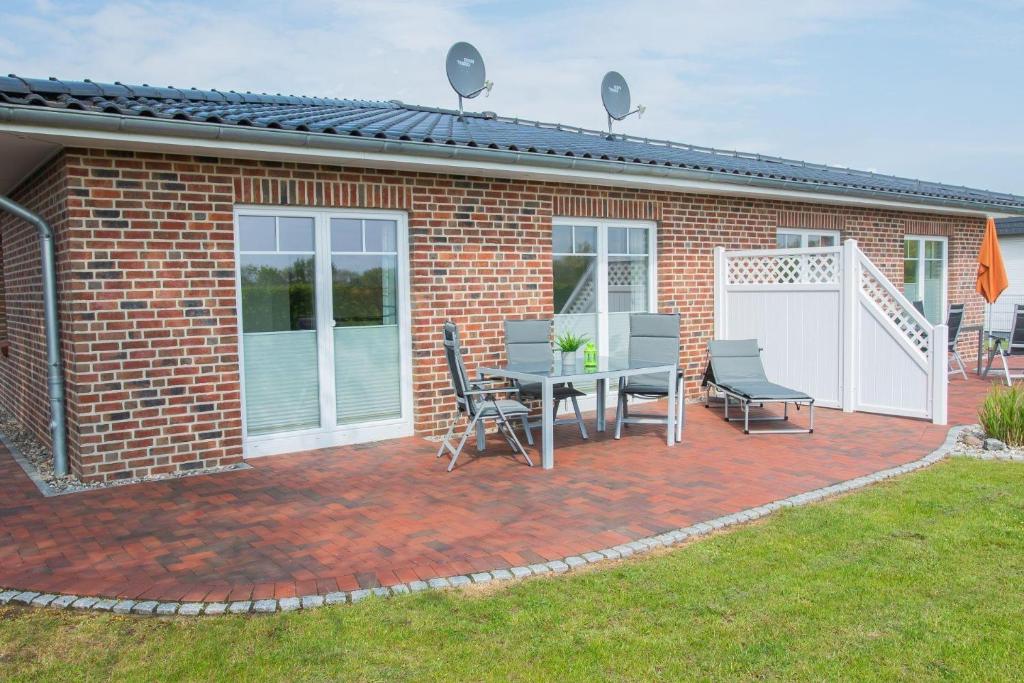 a brick house with a patio with a table and chairs at Am-Kampland-20-Lee in Dahme